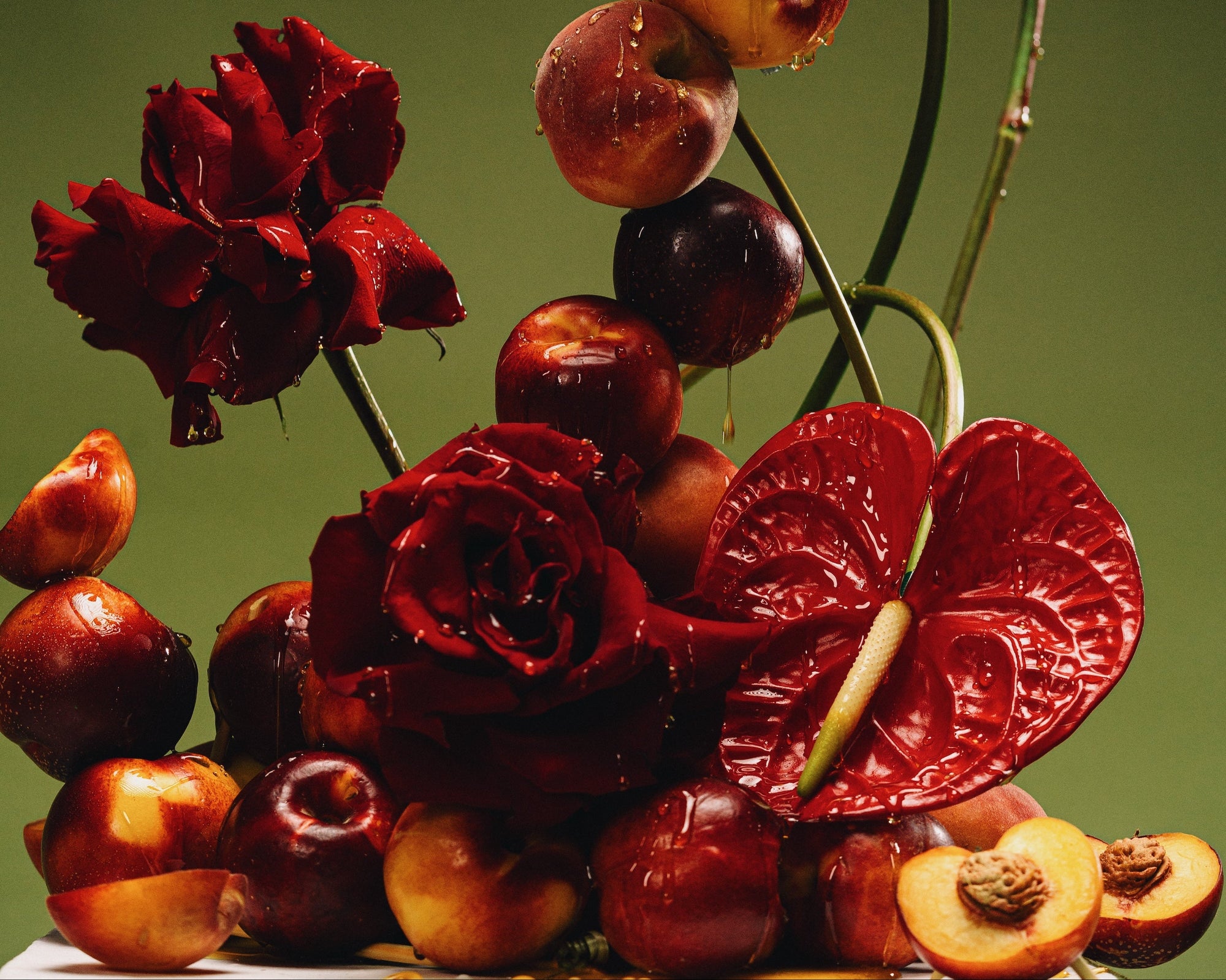 Artistic arrangement of red flowers and fruits on a dark background